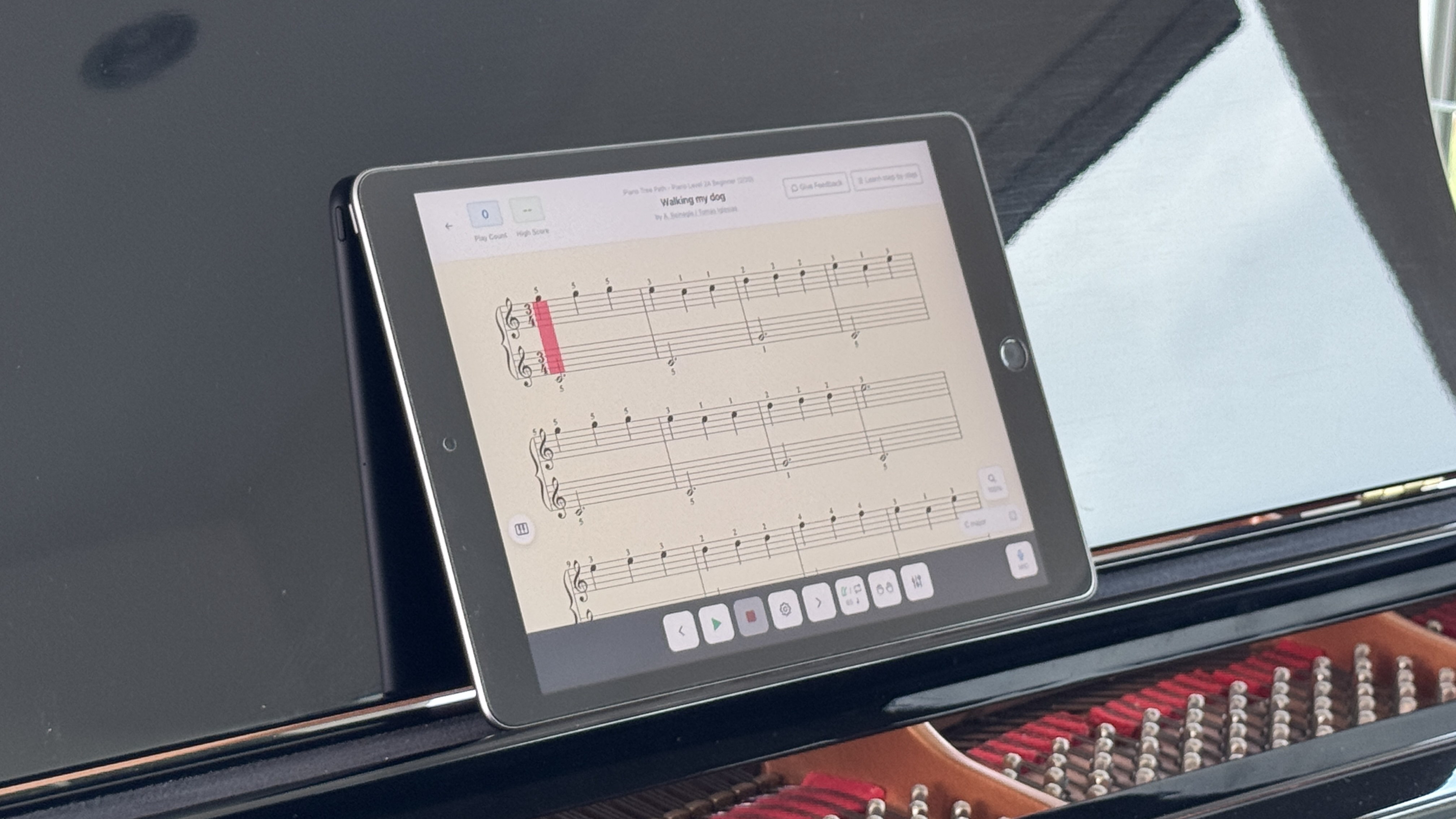 Teclado de piano con una tableta mostrando una app de lectura a primera vista en el atril